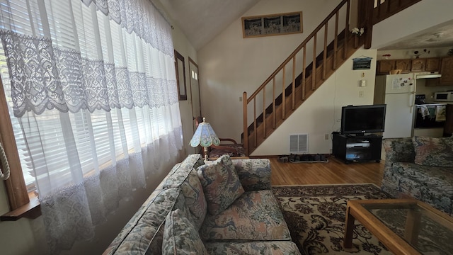 living room with a healthy amount of sunlight, stairs, wood finished floors, and visible vents
