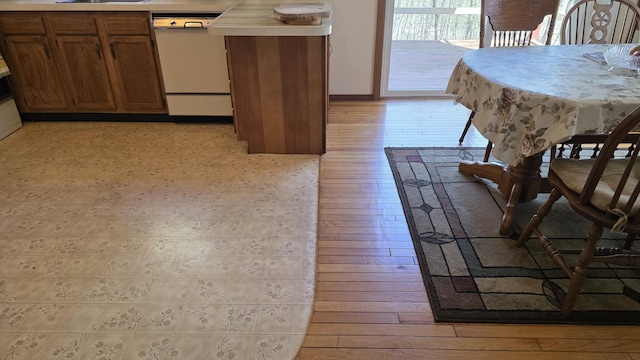 kitchen featuring light countertops, brown cabinets, light wood-style flooring, and dishwasher