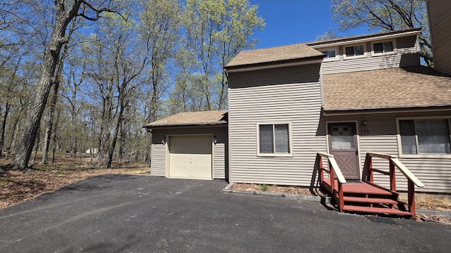 view of front of property with a garage, roof with shingles, and aphalt driveway