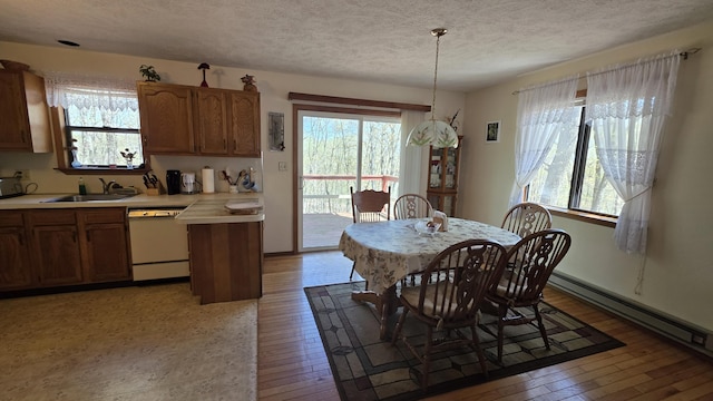 dining area with a baseboard heating unit, light wood-type flooring, and a textured ceiling