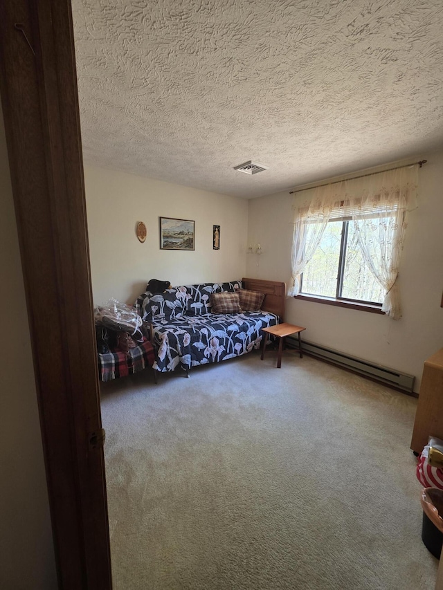 carpeted living area featuring a baseboard heating unit, a textured ceiling, and visible vents