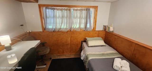 bedroom featuring wainscoting and wood walls