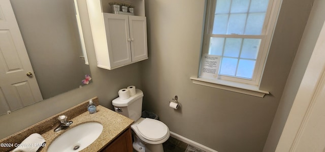 half bathroom with toilet, baseboards, and vanity