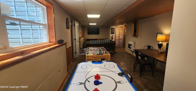 game room with a paneled ceiling, heating unit, and wood finished floors