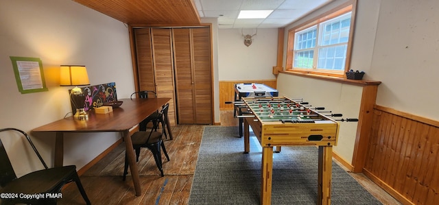 game room with a drop ceiling, wood walls, wainscoting, and wood finished floors