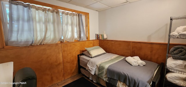 bedroom with a wainscoted wall and a paneled ceiling