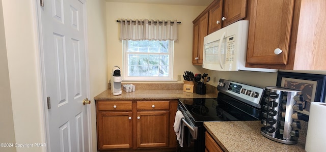 kitchen with brown cabinets, stainless steel electric range, and white microwave