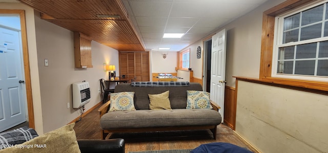 interior space with a paneled ceiling, heating unit, and wood finished floors