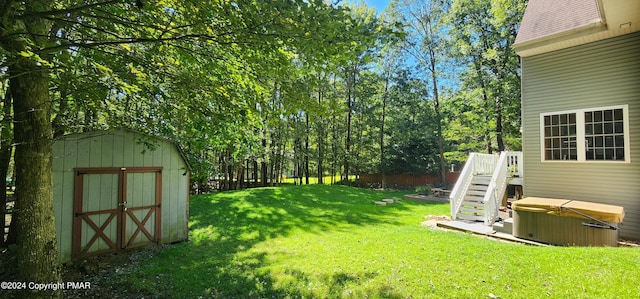 view of yard featuring an outdoor structure, a hot tub, and a storage shed