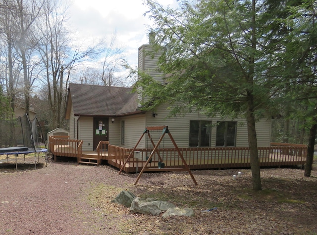 5 Bruin Ct, Lake Harmony, PA 18624 - view of front of house with a trampoline, roof with shingles, a wooden deck, and a chimney