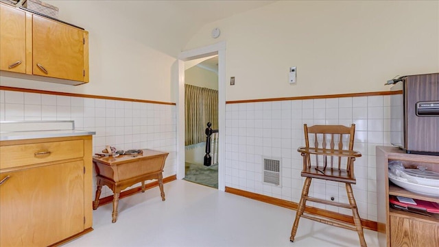 interior space with concrete floors, visible vents, tile walls, and wainscoting