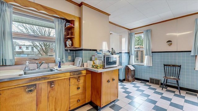 kitchen featuring light floors, visible vents, ornamental molding, light countertops, and stainless steel microwave