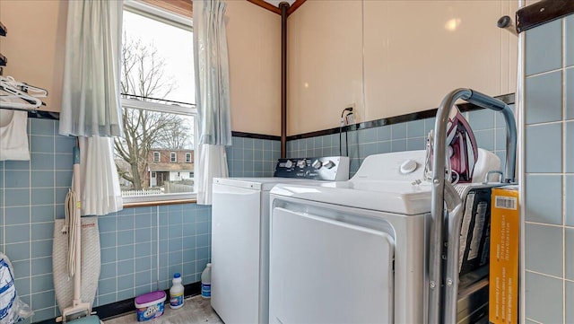 clothes washing area with tile walls, cabinet space, and independent washer and dryer