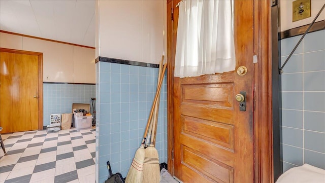 bathroom with tile patterned floors, toilet, tile walls, and ornamental molding