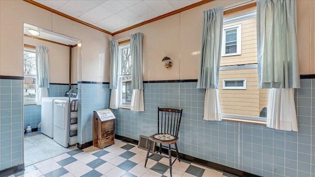 bathroom featuring washing machine and clothes dryer, wainscoting, and ornamental molding