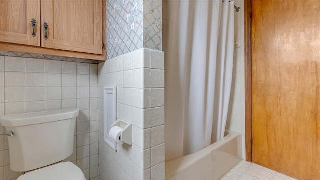 bathroom with tile walls, toilet, and shower / bath combo