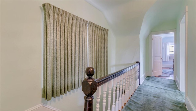 corridor featuring lofted ceiling, carpet, and baseboards