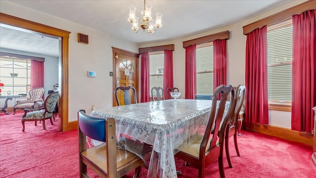 carpeted dining space with a notable chandelier and baseboards