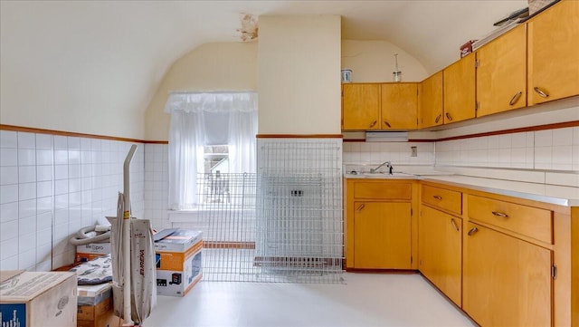 kitchen with vaulted ceiling, light countertops, tile walls, and a sink