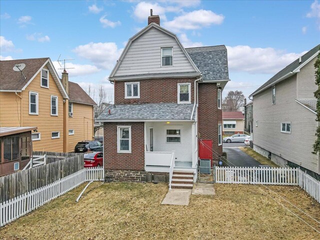 back of property featuring brick siding, roof with shingles, cooling unit, a chimney, and a fenced backyard