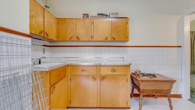 kitchen featuring a sink, tile walls, and light countertops