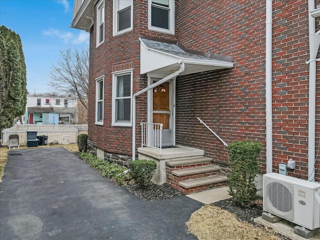 entrance to property with ac unit, fence, and brick siding