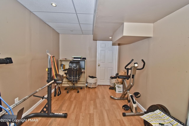 exercise room with a paneled ceiling, baseboards, and wood finished floors