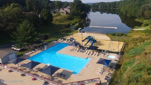 community pool with a water view, a patio, and a forest view