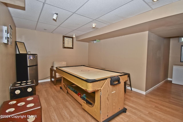 game room with light wood-style floors, baseboards, and a drop ceiling