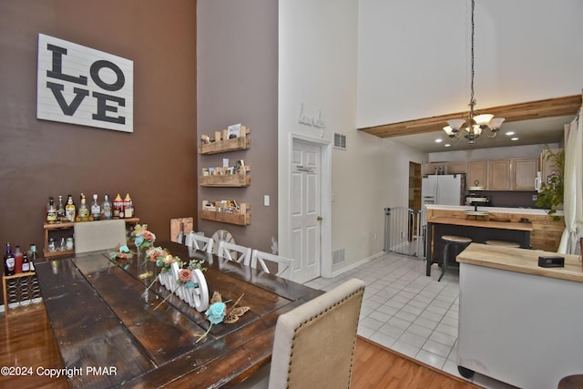 dining area with light tile patterned floors, a notable chandelier, a towering ceiling, baseboards, and visible vents