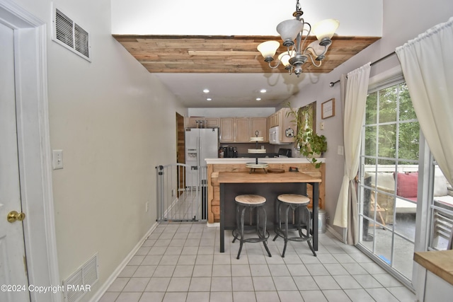 kitchen with white appliances, light tile patterned floors, visible vents, and an inviting chandelier