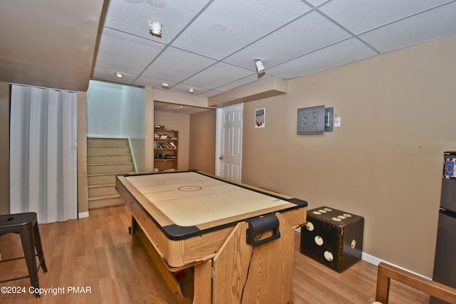 rec room featuring baseboards, a paneled ceiling, and light wood-style floors