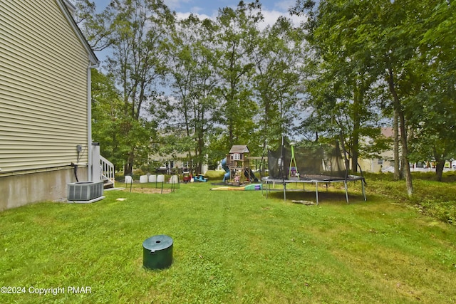 view of yard featuring a trampoline, a playground, and central air condition unit