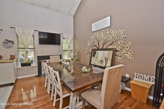 dining space with high vaulted ceiling, baseboards, and wood finished floors