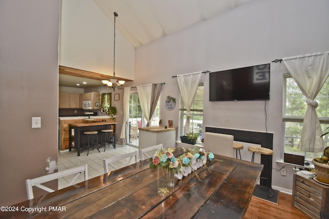 dining space with a chandelier, light wood-style flooring, high vaulted ceiling, and baseboards