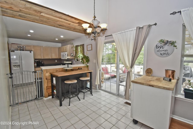 kitchen with light tile patterned flooring, a notable chandelier, white appliances, butcher block counters, and pendant lighting