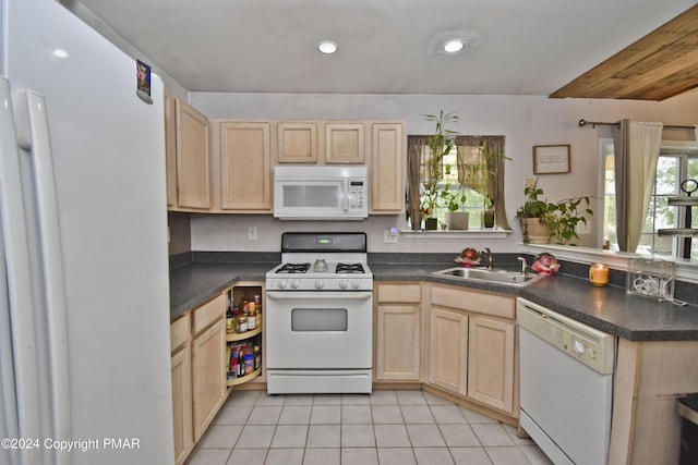 kitchen featuring a sink, white appliances, dark countertops, and light brown cabinets