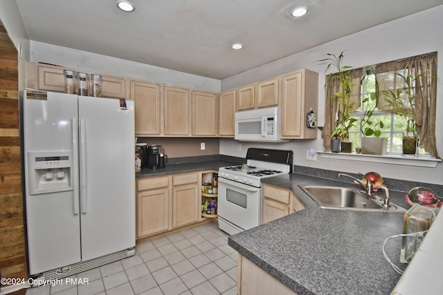 kitchen with dark countertops, white appliances, a sink, and light brown cabinetry