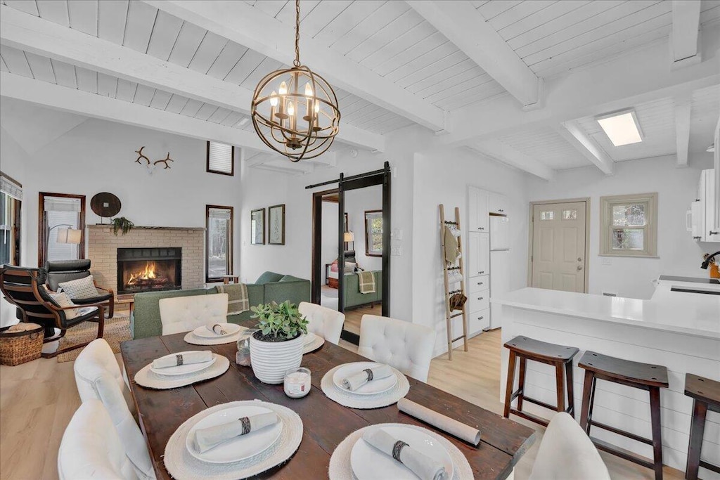 3289 Greenbriar Dr, East Stroudsburg, PA 18301 - dining space featuring a barn door, light wood finished floors, a notable chandelier, and a fireplace