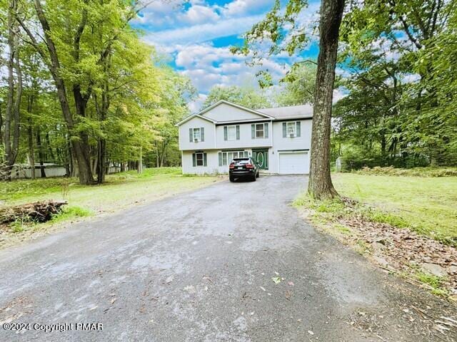 bi-level home featuring aphalt driveway, a front lawn, and a garage