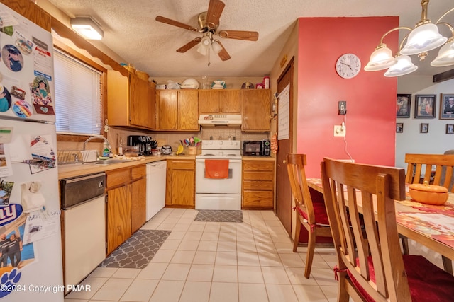 kitchen featuring light tile patterned floors, under cabinet range hood, white appliances, a sink, and light countertops