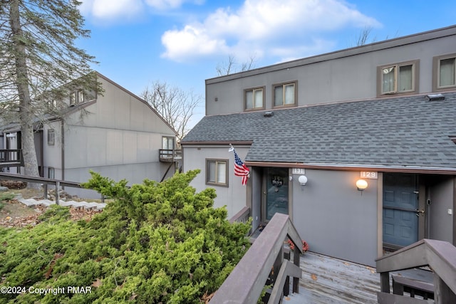 view of front of house with a shingled roof and stucco siding