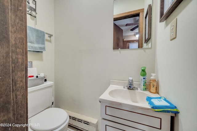 half bathroom featuring a baseboard heating unit, vanity, and toilet