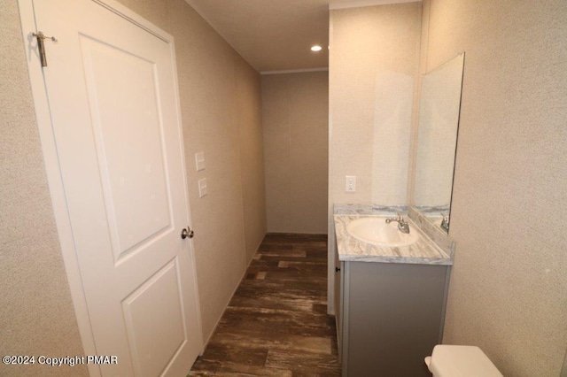 bathroom featuring toilet, recessed lighting, wood finished floors, and vanity