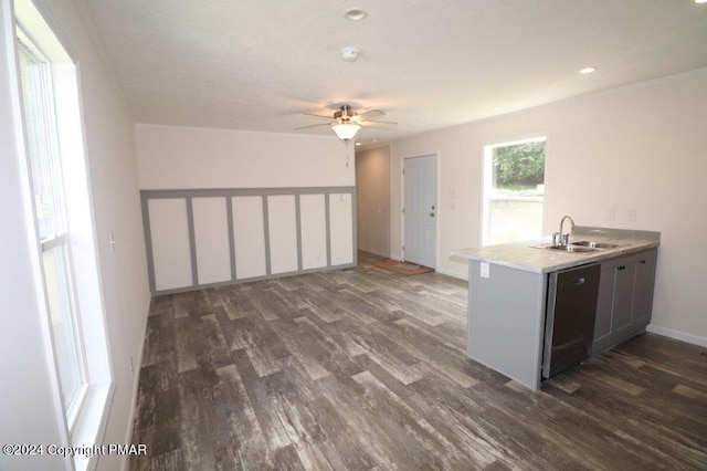 kitchen with dark wood finished floors, light countertops, stainless steel dishwasher, a sink, and a peninsula