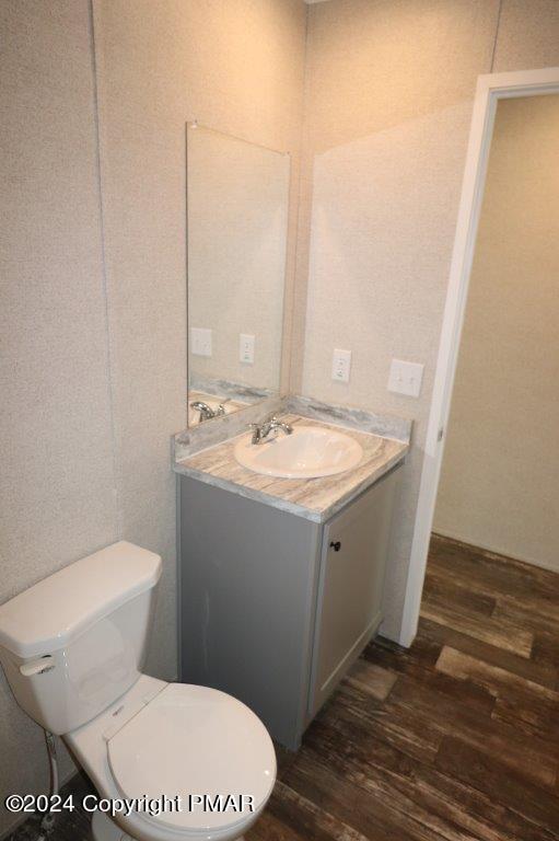 bathroom with toilet, wood finished floors, and vanity