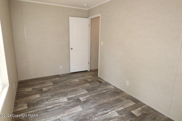 spare room with ornamental molding and wood finished floors