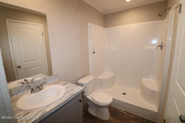 bathroom with toilet, walk in shower, wood finished floors, and vanity