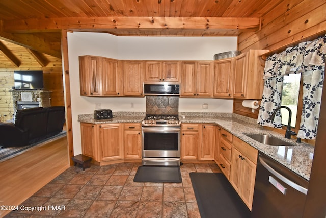 106 Windsor Dr, Lake Ariel, PA 18436 - kitchen featuring appliances with stainless steel finishes, a wood ceiling with exposed beams, wooden walls, light stone countertops, and a stone fireplace
