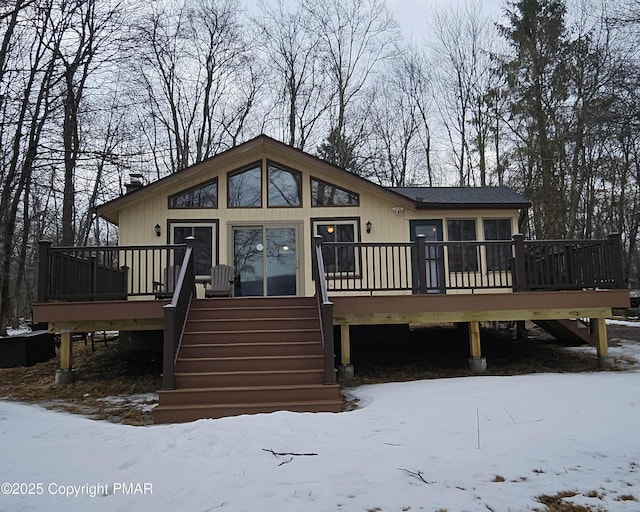 snow covered rear of property with stairway and a wooden deck